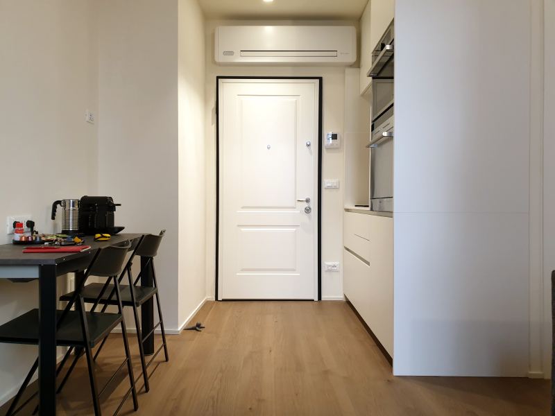 Entrance with white door, air conditioner and dining table on the left